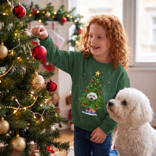 Girl decorating the tree in a forest green kids' Christmas tree pet face sweatshirt with her bichon frise