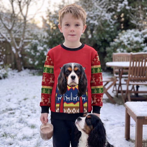 Boy in the snowy garden in a kids' premium custom pet face Christmas sweatshirt with his Cavalier