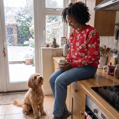 Woman with coffee in the kitchen wearing a custom pet face pattern Christmas sweatshirt, her cavapoo at her feet
